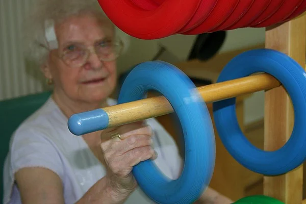 Bewohnerin nimmt Therapie-Ringe von einer waagerechten Stange