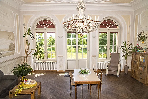 Musikzimmer im Schloss Meerholz mit hoher Decke, großer Fensterfront, Sitzgelegenheiten und Tischen