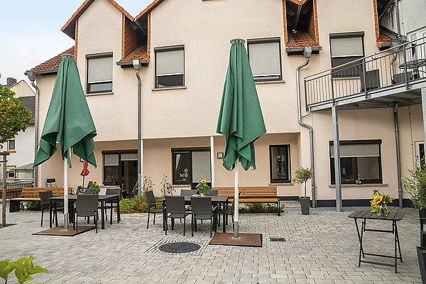 Gepflasterter Hof des Haus Ysenburg mit großen Sonnenschirmen und mehreren Sitzgelegenheiten