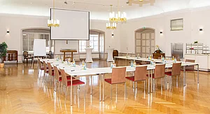 Kaisersaal des Schloss Meerholz mit Leinwand und Flip-Chart, davor in U-Form gestellte Tische mit Getränken