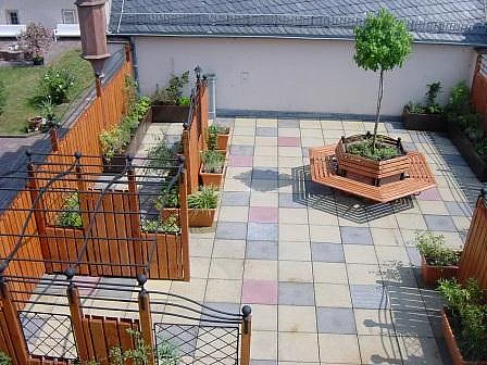 Begrünte Dachterrasse in der Sonne mit vielen Sitzgelegenheiten